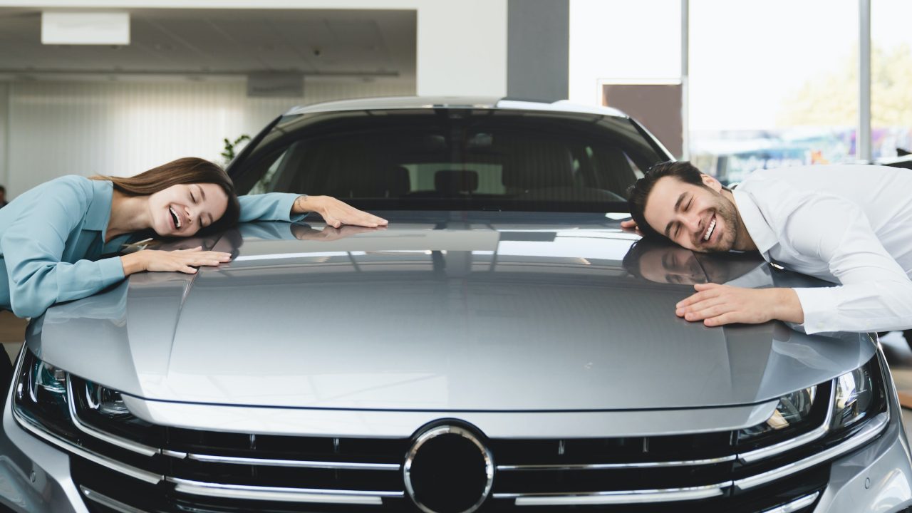 Family hugging their new car, feeling excited after buying expensive auto at auto dealer shop store
