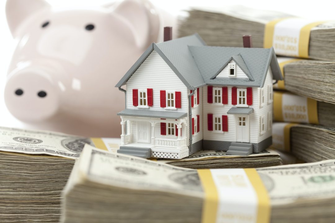 Small House and Piggy Bank with Stacks Money. Symbolizing a shared equity loan for homes.