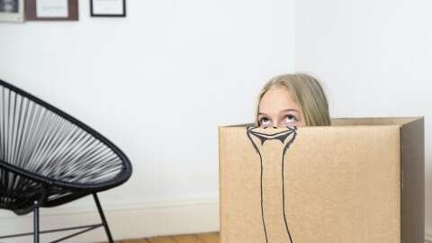 Girl inside a cardboard box painted with an ostrich