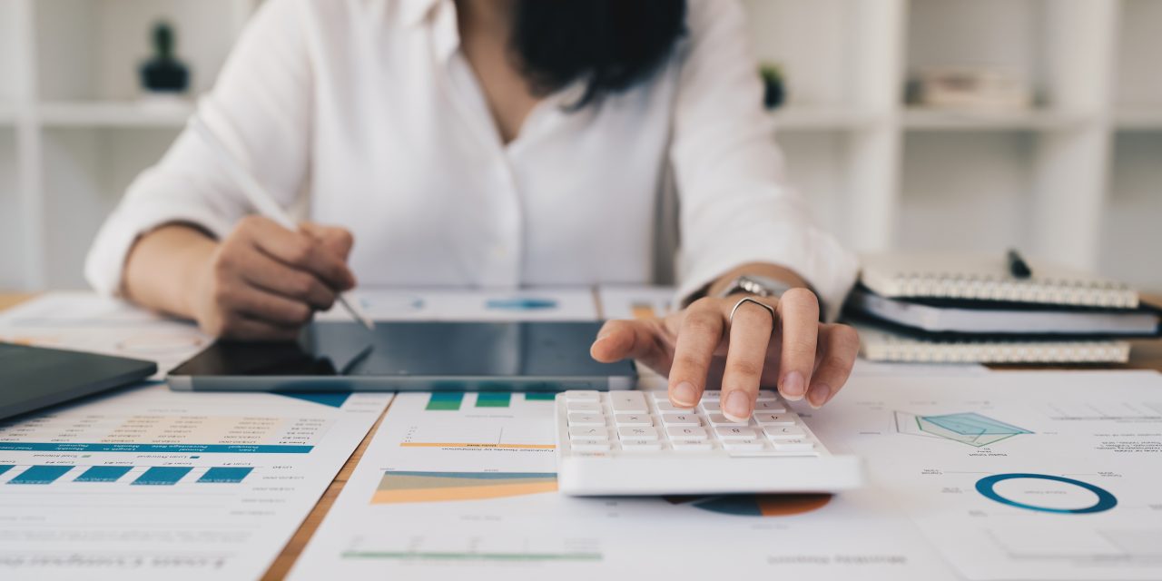 Asian Business Woman analyzing with calculator and paperwork on desk